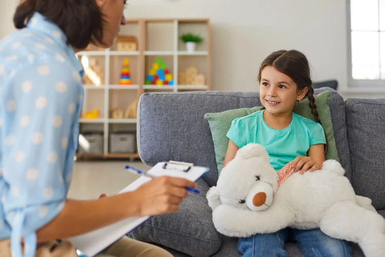 Enfant chez un psy avec un nounours en peluche sur les genoux